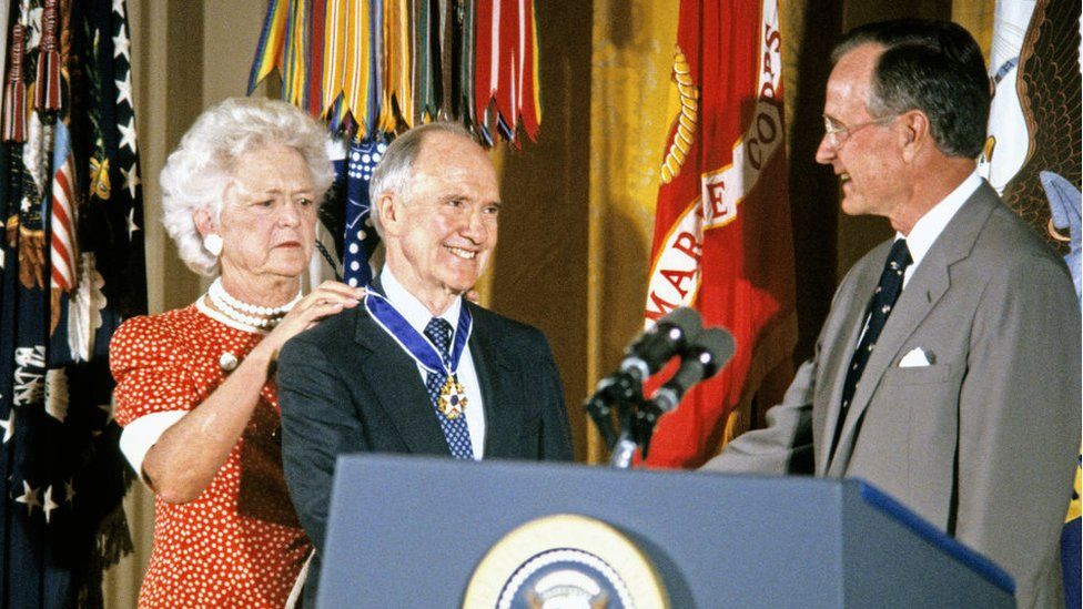 US First Lady Barbara Bush fastens the Presidential Medal of Freedom around the neck of National Security Advisor Brent Scowcroft as he shakes hands with US President George HW Bush