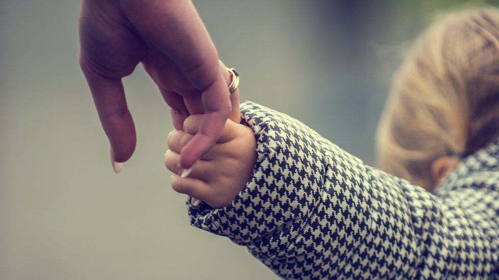 A woman's hand holding a child's hand