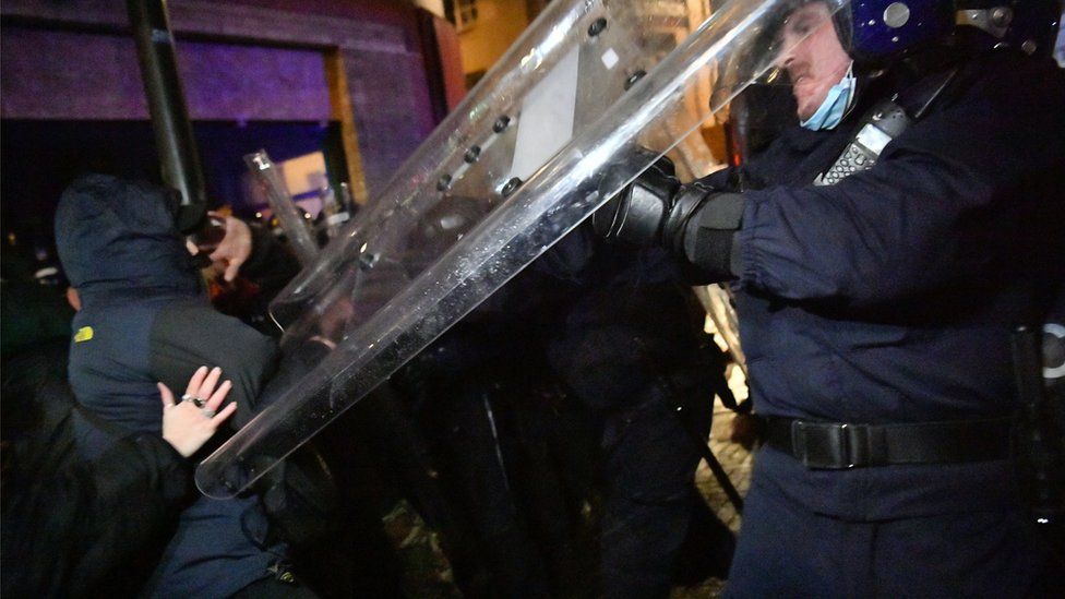 Police officers hits protester with riot shield