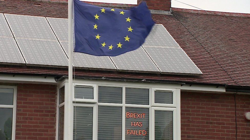 Brexit has failed sign in a window and an EU flag outside a house