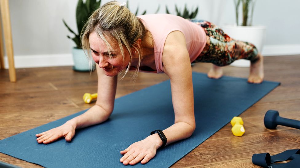 A woman does a plank exercise at home