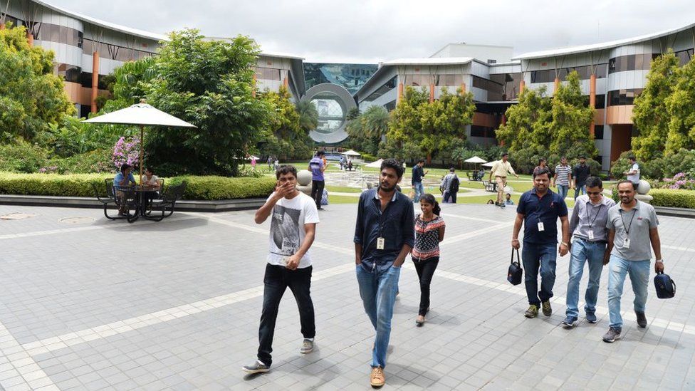 Employees of Indian Software giant Infosys Technologies Limited walk in the campus of the company's headquarters in Bangalore on July 14, 2017.