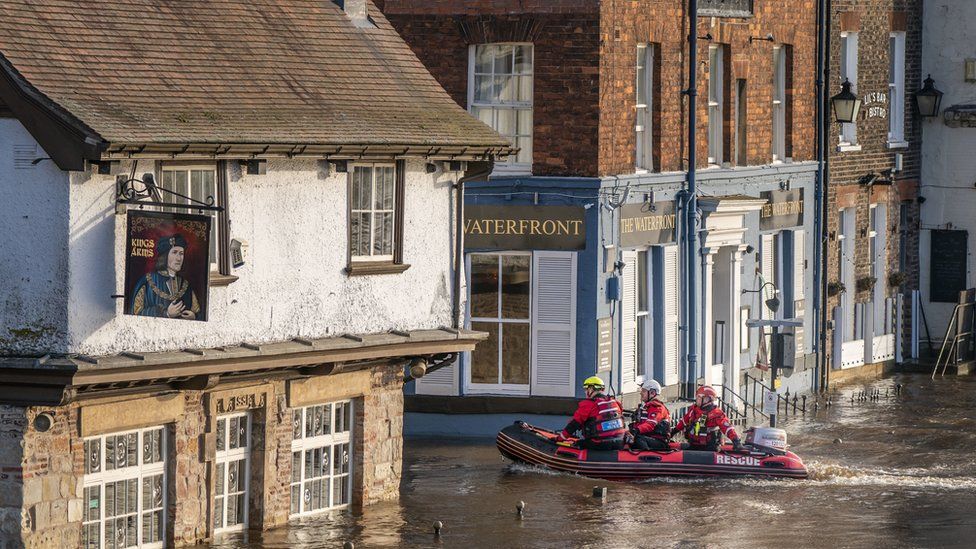 Rescue workers use a boat to navigate the floodwater in the centre of York