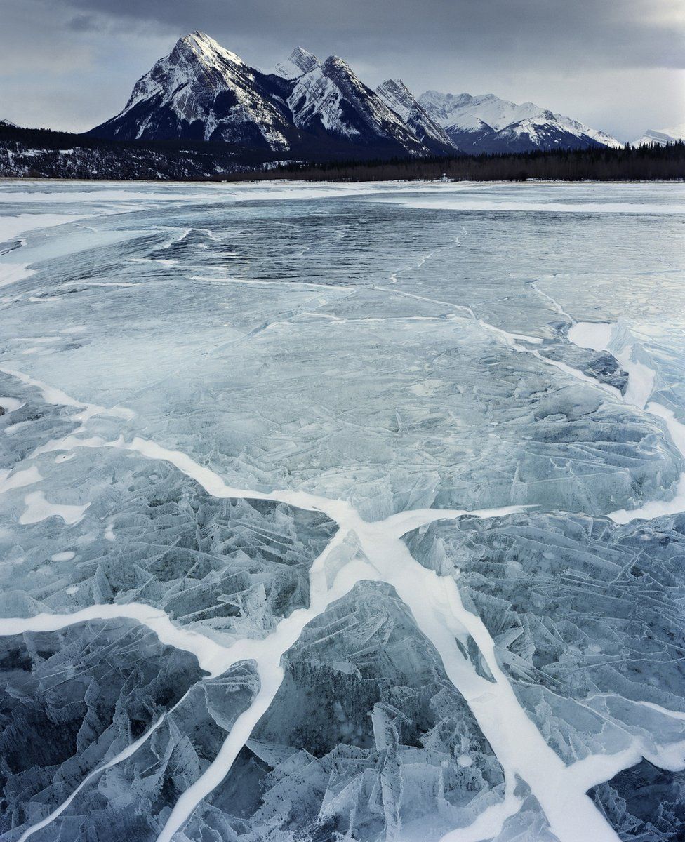 A frozen Abraham Lake in Alberta, Canada, with show capped mountains in the distance. Photographed by Paul Wakefield 2011.