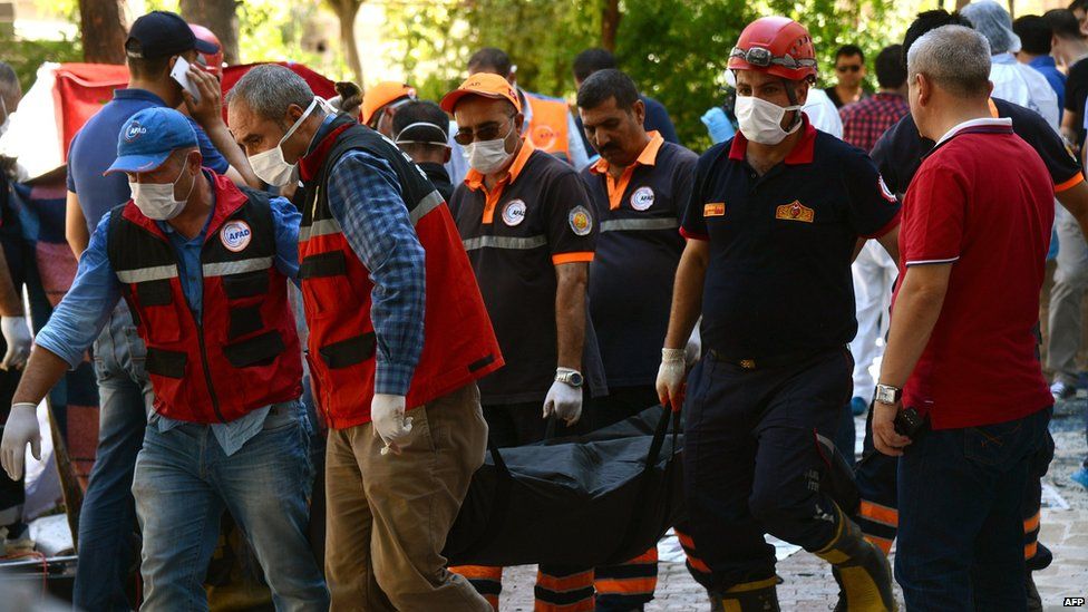 Officials carry the bodies of victims after an explosion in the town of Suruc, Turkey (20 July 2015)