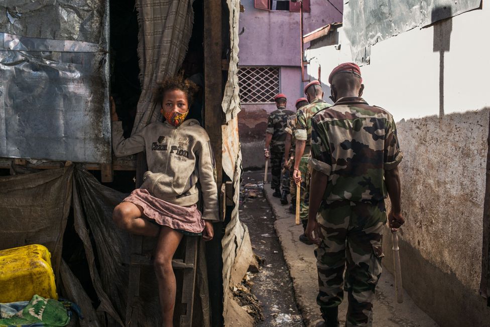 A child wearing a protective mask sits as members of the army patrol the streets of Antananarivo, Madagascar, on 24 April 2021