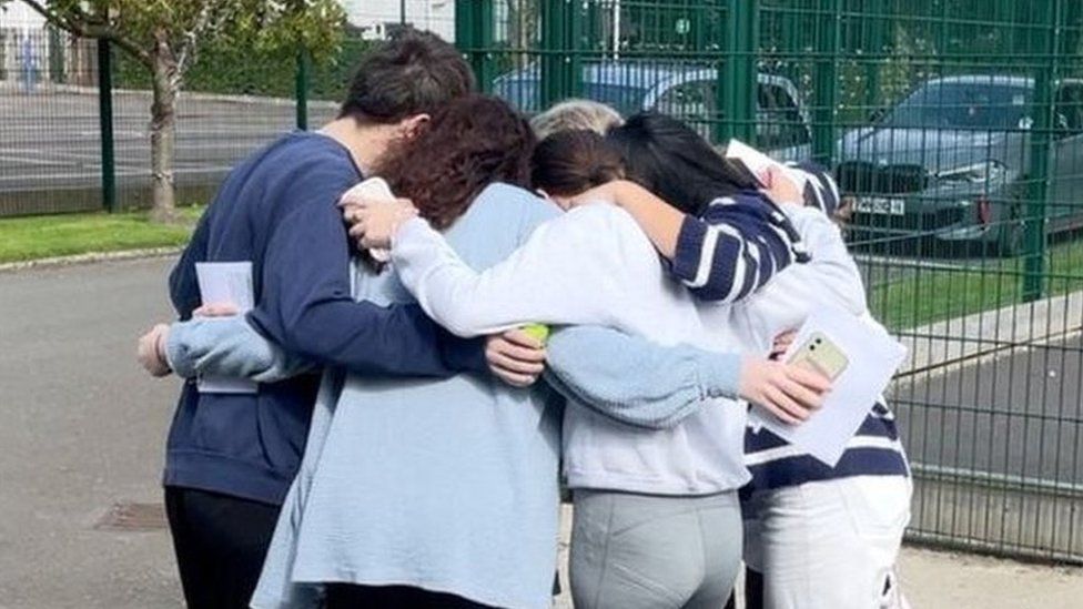Students group hug after getting A-level results