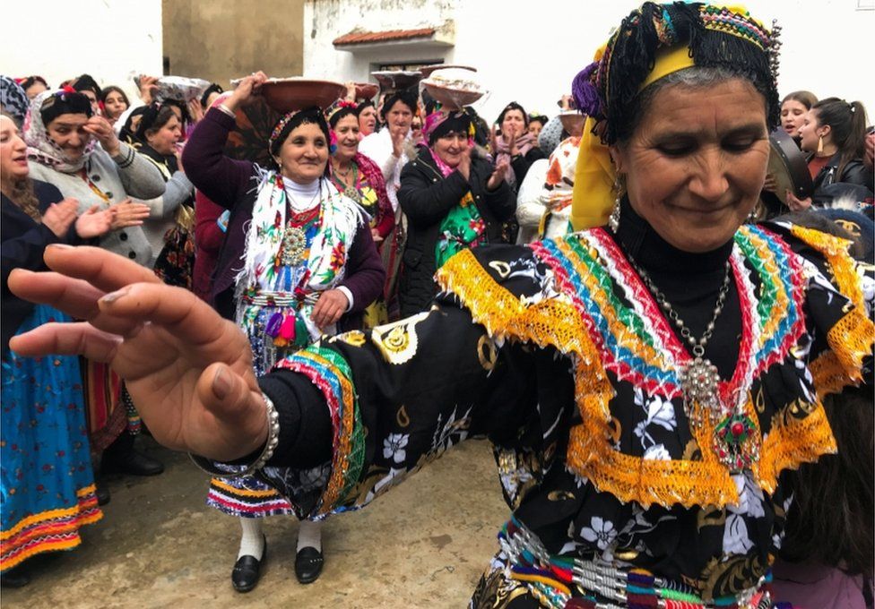 Women dance, carry goods, and clap their hands.