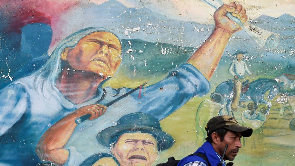 An indigenous man walks next to a mural on October 30, 2019, during a meeting following the recent murder of an indigenous leader and four guards by suspected rebels, close to a checkpoint in Tacueyo, in the rural area of Toribio, department of Cauca, Colombia.