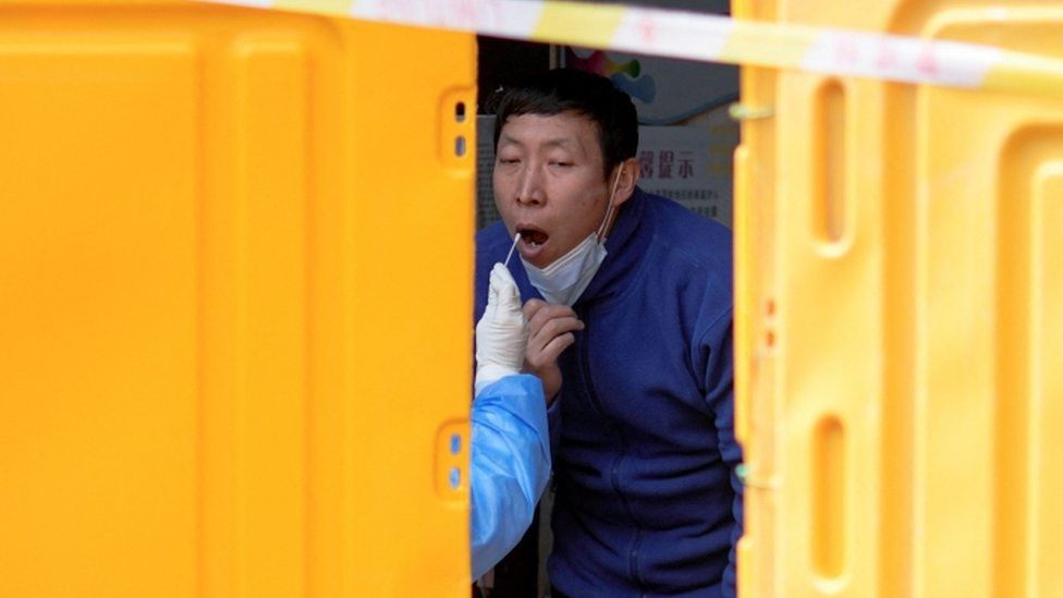 A man gets tested for Covid-19 at a makeshift testing site behind barriers of an area under lockdown in Shanghai.