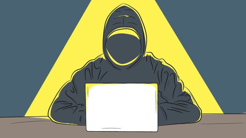 Illustration of a shadowy figure in a hoodie at a computer in a pool of light