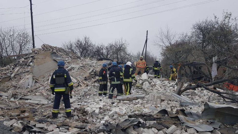 Emergency workers climb across a huge pile of rubble