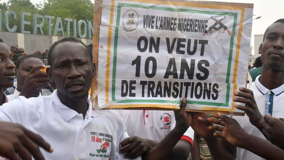 Two men holding a placard in support of the coup in Niger during a demonstration outside the national assembly in Niamey