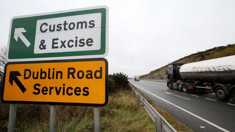 A tanker lorry travels past a roadside sign that reads: Customs & Excise