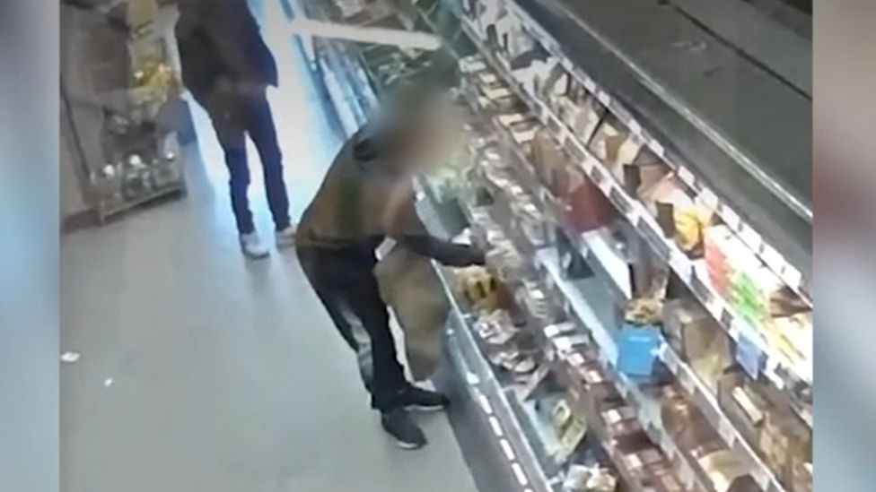 A shoplifter filling a bag with meat in a supermarket