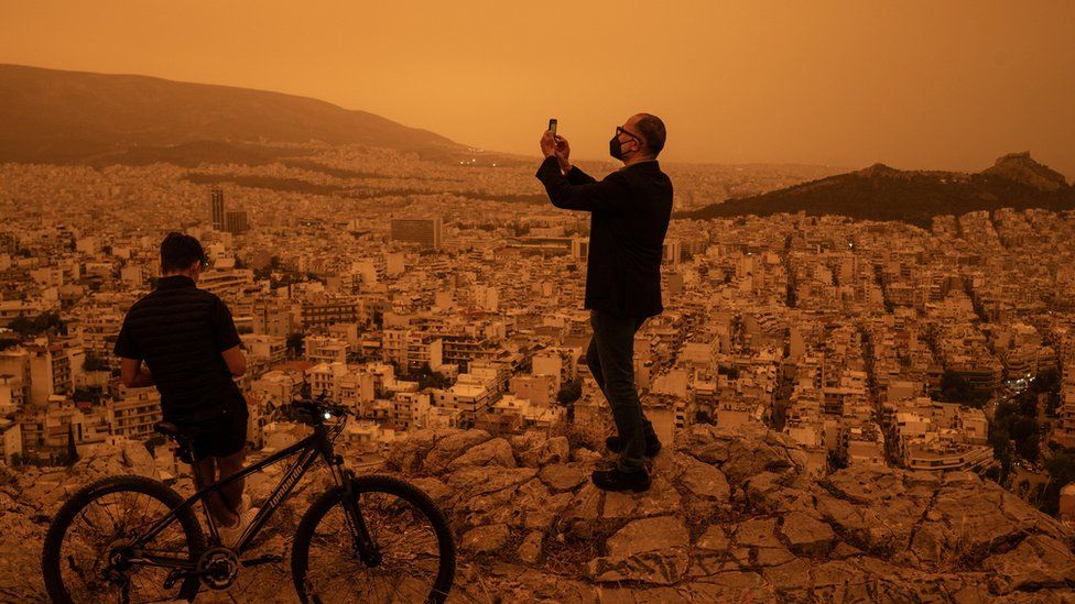 A man takes a photograph of the city of Athens
