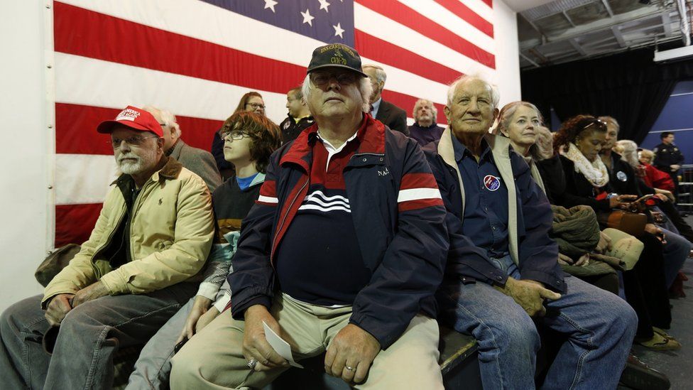 Donald Trump supporters sitting in front of an American flag