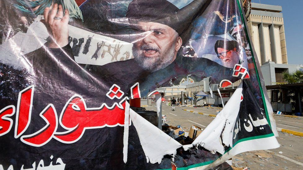 A torn banner showing Iraqi cleric Moqtada al-Sadr hangs in Baghdad following deadly clashes between his supporters and security forces and rival militias (30 August 2022)