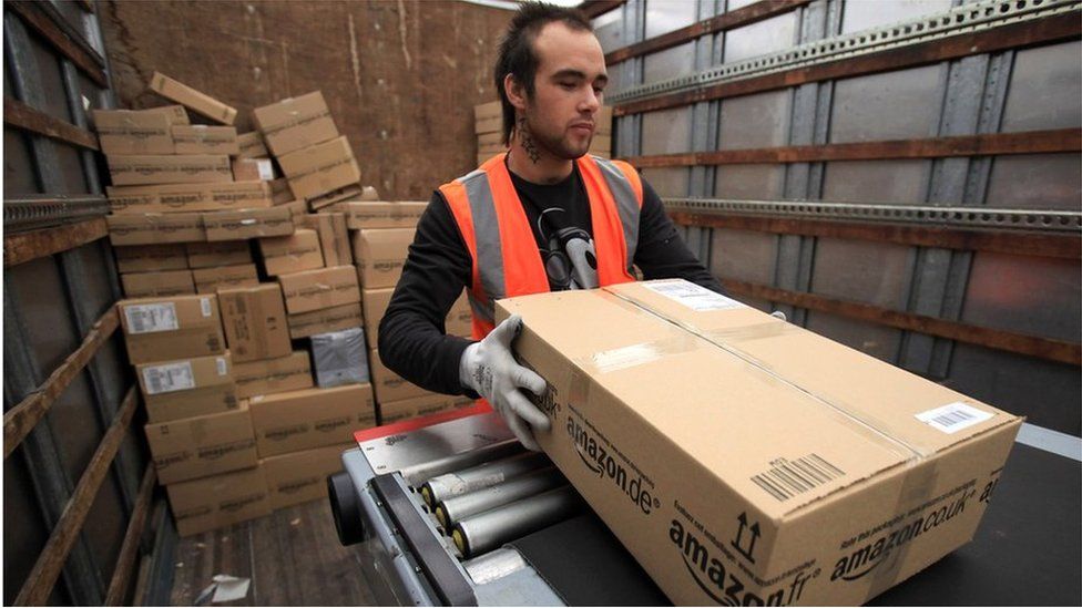 An Amazon worker loads a package on a truck