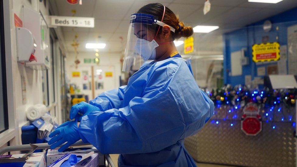 Nurse in PPE in hospital with Christmas decorations in the background