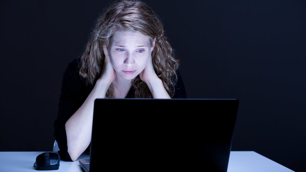 woman looking at laptop screen in distress