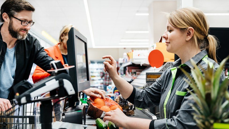 Изображение женщины на кассе супермаркета, обслуживающей мужчину