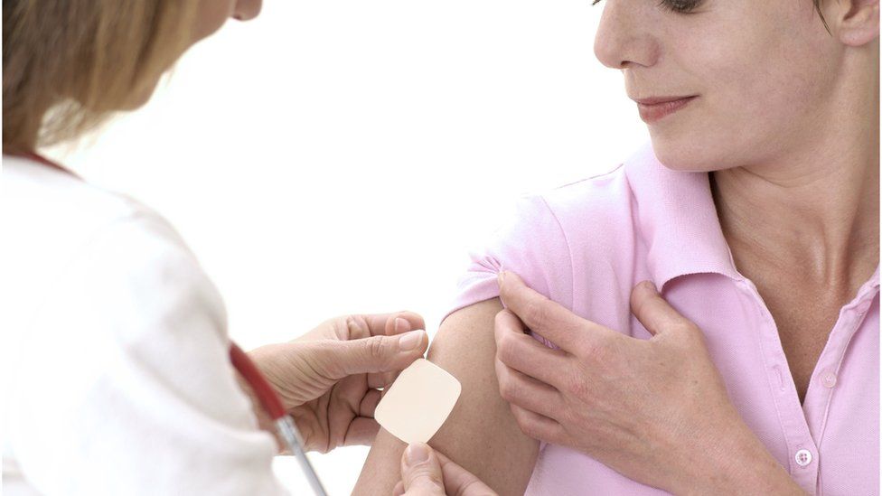 Woman receiving an HRT patch from a doctor