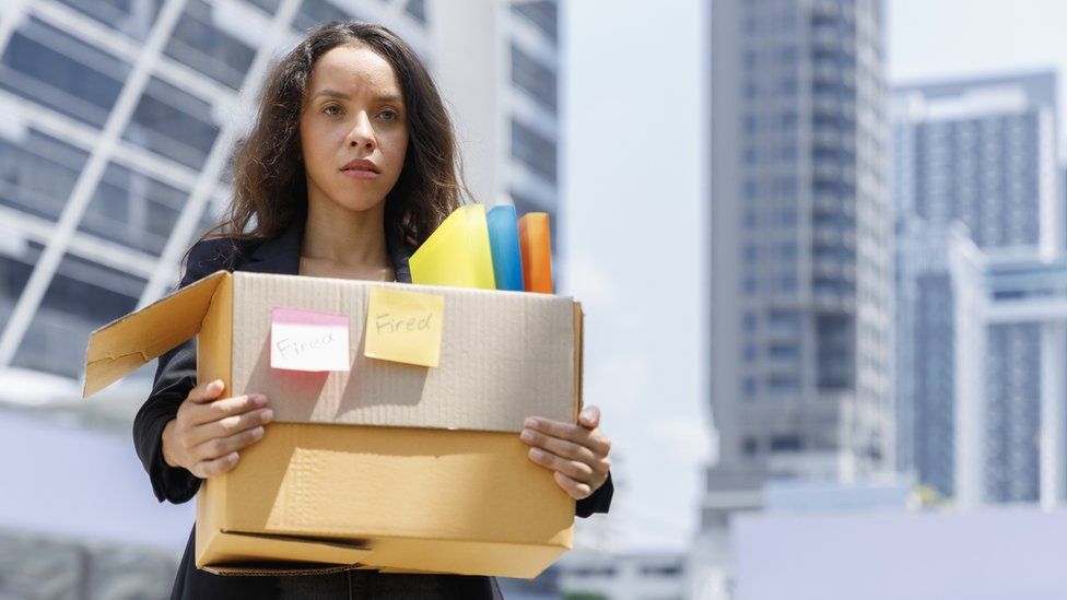 A stock image of a sacked worker with their possessions in a cardboard box