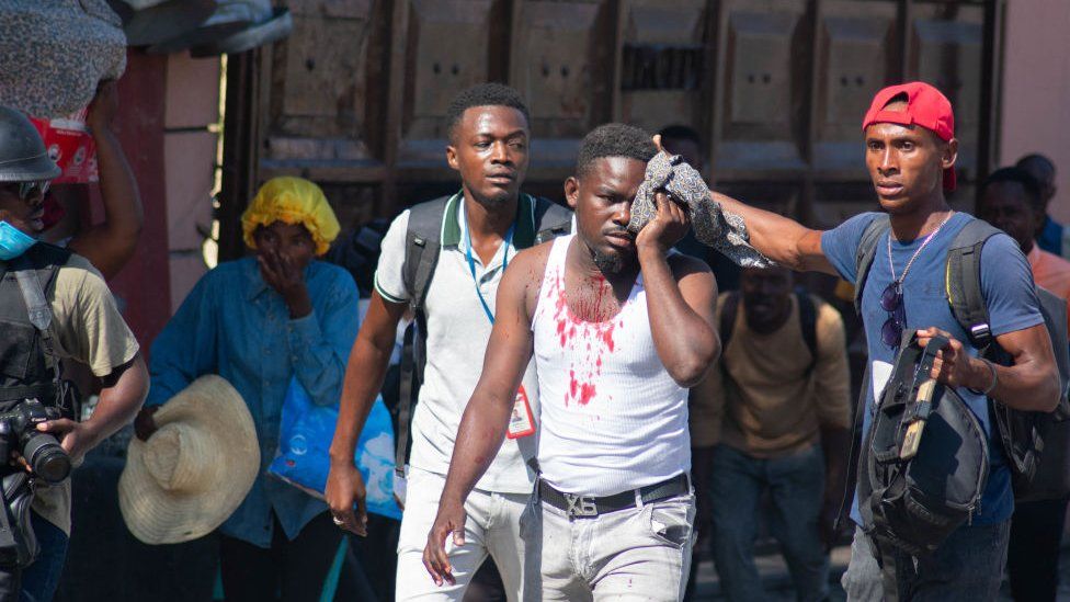 An injured man is helped by colleagues during violence in Port-au-Prince this month