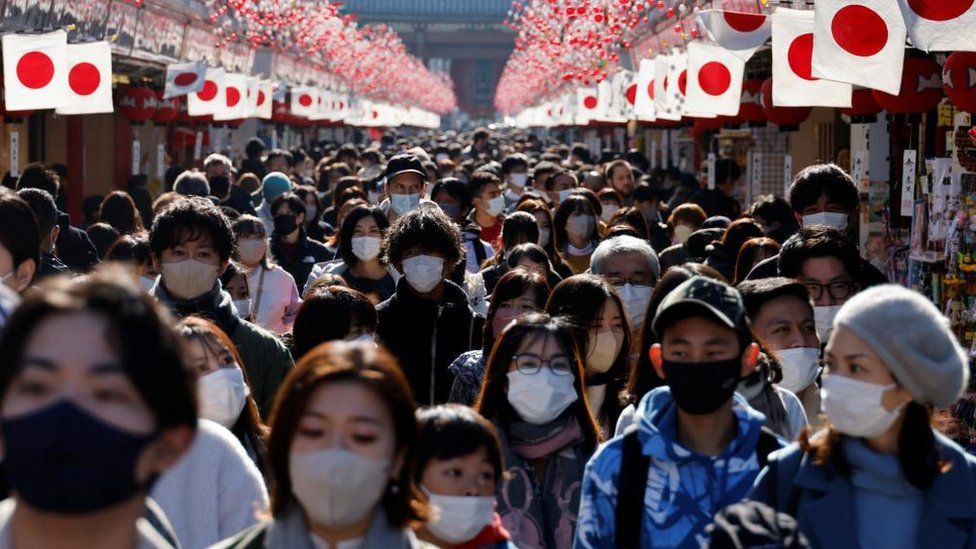 นักท่องเที่ยวสวมหน้ากากป้องกันเดินภายใต้การตกแต่งสำหรับปีใหม่ที่ถนนนากามิเสะที่นำไปสู่วัดเซ็นโซจิที่ย่านอาซากุสะ แหล่งท่องเที่ยวยอดนิยม ท่ามกลางการแพร่ระบาดของโรคติดเชื้อไวรัสโคโรนา (โควิด-19) ในกรุงโตเกียว ประเทศญี่ปุ่น