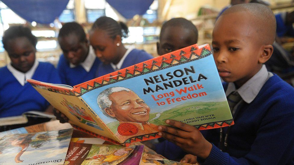 Photos shows a Kenyan schoolboy reading a book on former South African president Nelson Mandela
