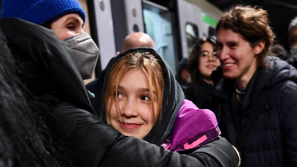 A woman welcomes a child who has arrived at Berlin's central station on a train from Poland, amid Russia's invasion of Ukraine