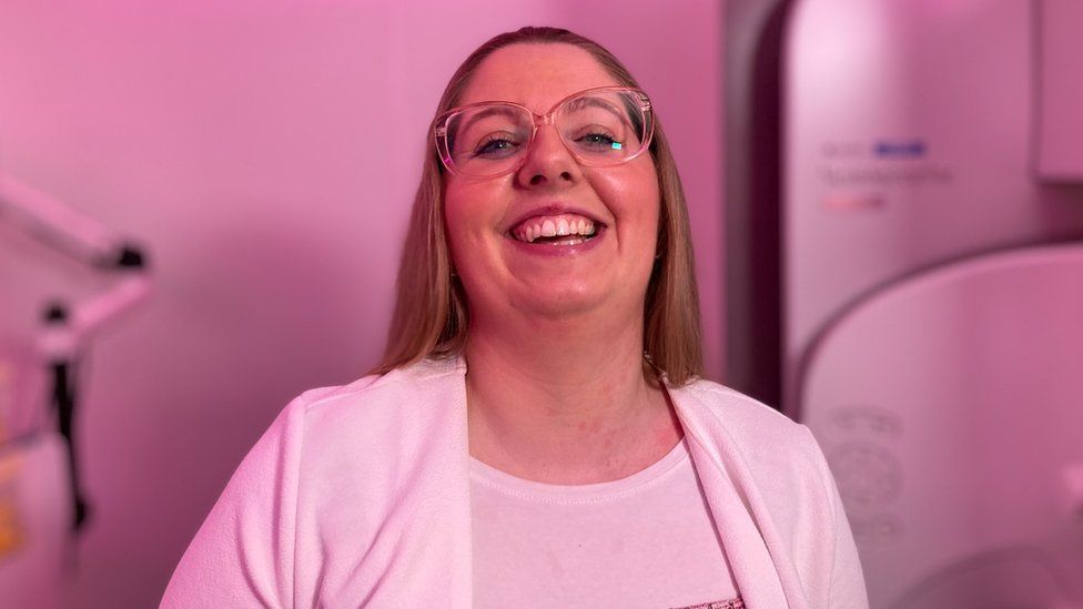 A woman in glasses smiles at the camera