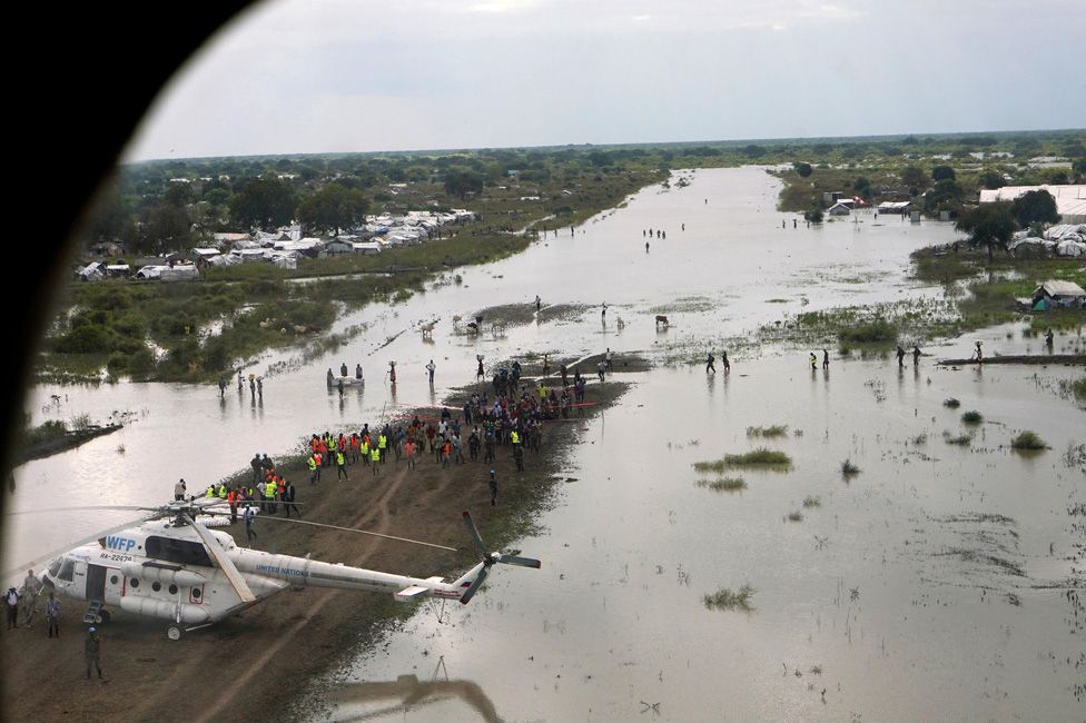 A WFP (World Food Program) helicopter is seen on the flooded airstrip, after heavy rains and floods forced hundreds of thousands of people to leave their homes, in the town of Pibor, Boma state