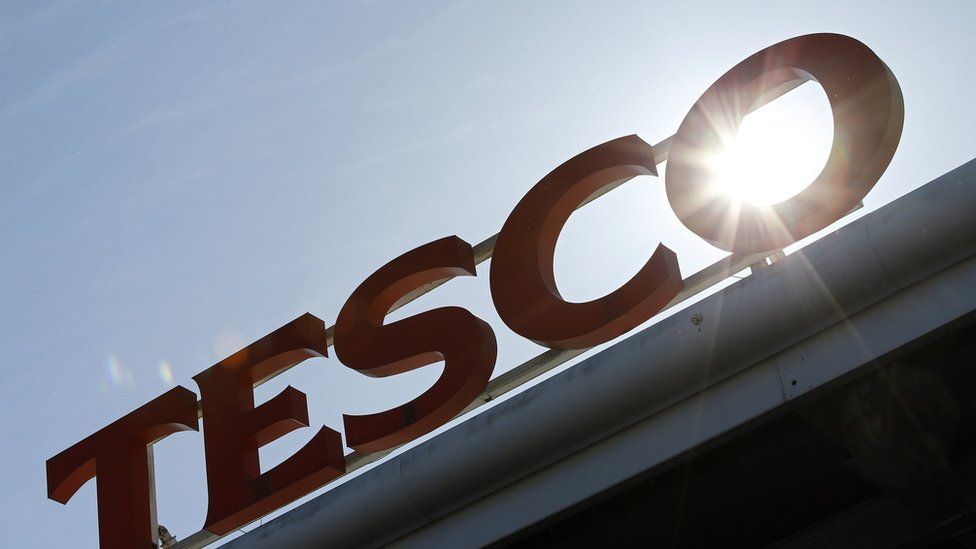 Tesco sign with sun behind it