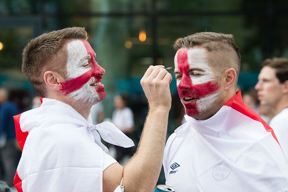 England football fans paint their faces as they arrive at Wembley Stadium ahead of England match against Denmark in the semi-final of Euro 2020 Championship