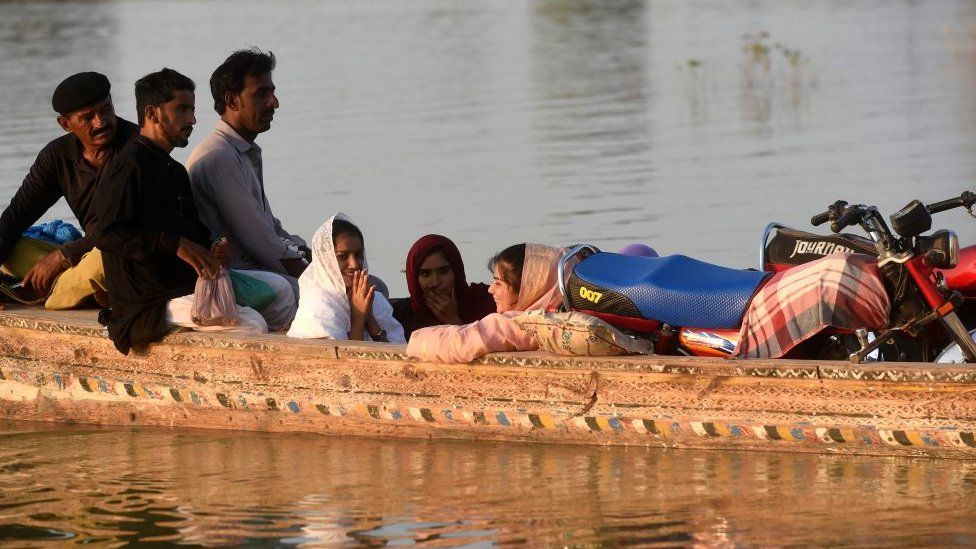 People crowded together on a boat in a flooded area in Pakistan
