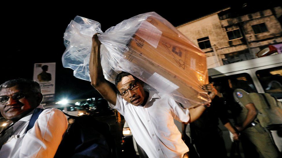 An election official in Colombo carrying a ballot box on his back