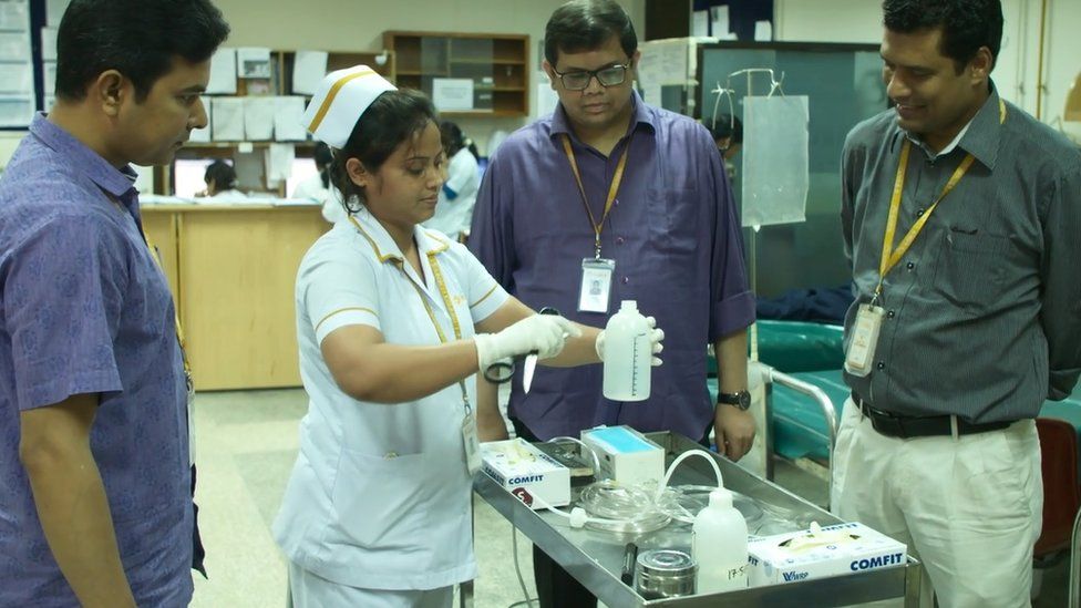 Doctors and a nurse look at at the plastic bottle lifesaving invention