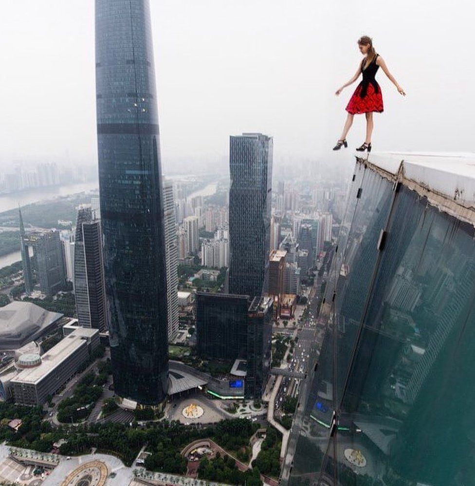 Angela Nikolau dangling her foot over the edge of a high rise building