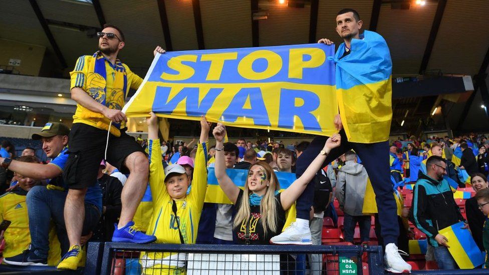 Ukraine fans hold up a flag saying 'Stop war'