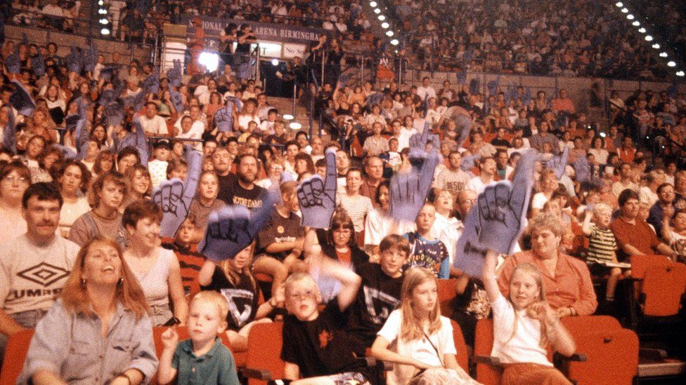 The crowd at the National Indoor Arena in Birmingham with many holding aloft "foam fingers"