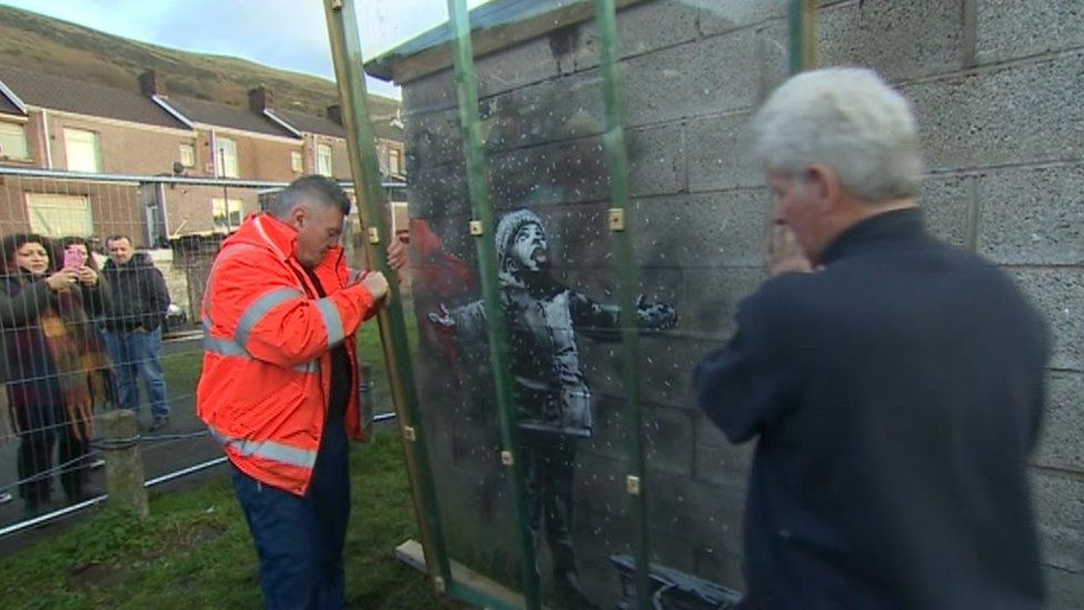 Plastic sheet being placed over the Banksy artwork in Port Talbot