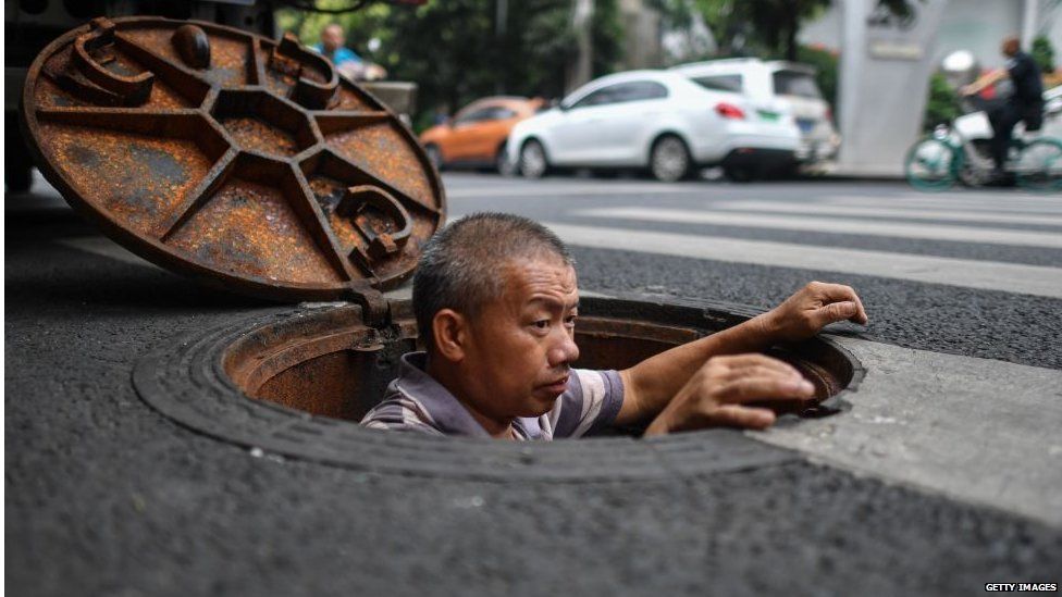 A man worksing in a manhole in Chengdu, China