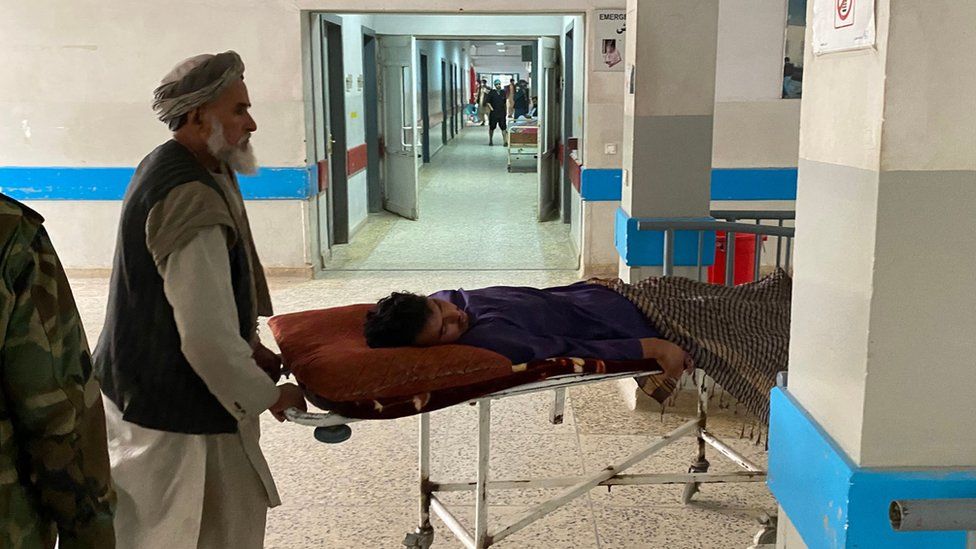Мужчины переносят раненого в больницу в Мазари-Шарифе 9 марта 2023 года после нападения террориста-смертника на офис талибского губернатора афганской провинции Балх.