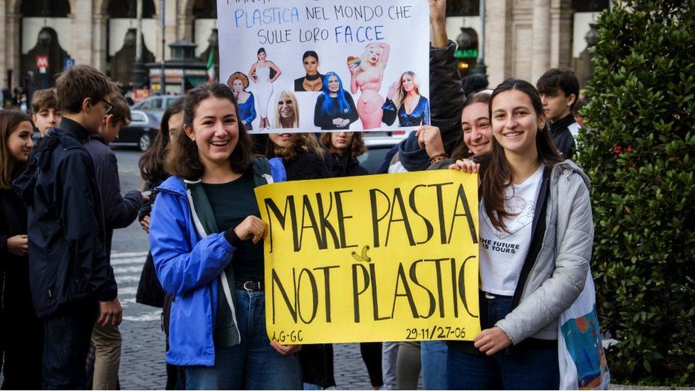 Climate activists holding a "make pasta not plastic" sign