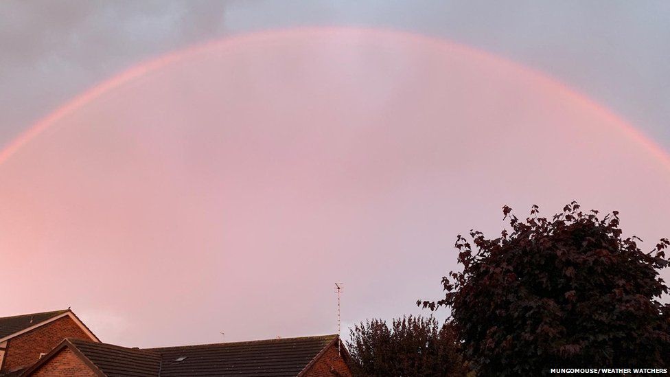 Pink rainbow arches over a house