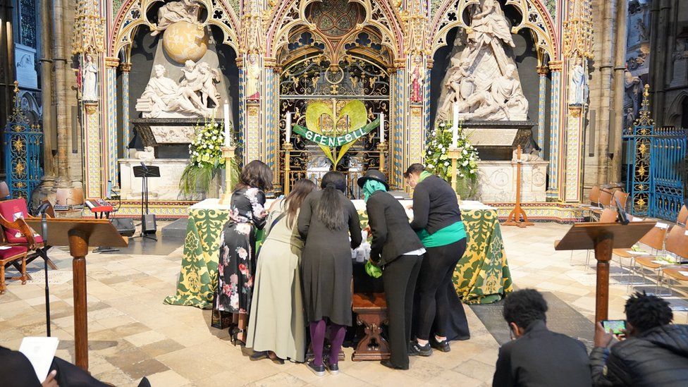 People arrive for a Grenfell fire memorial service and place items at the altar at Westminster Abbey in London