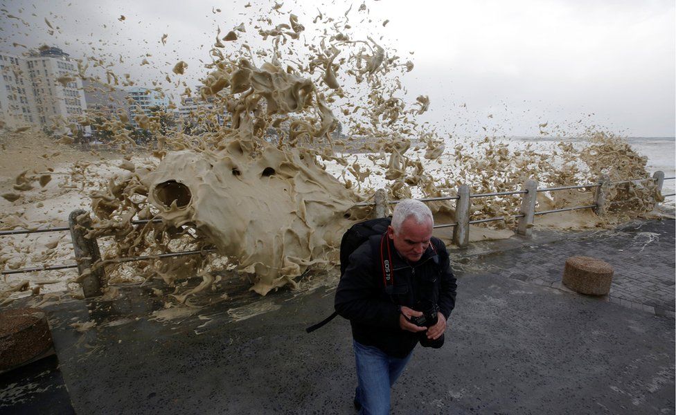 A man runs from sea spray as storms hit Cape Town, South Africa, June 7, 2017.