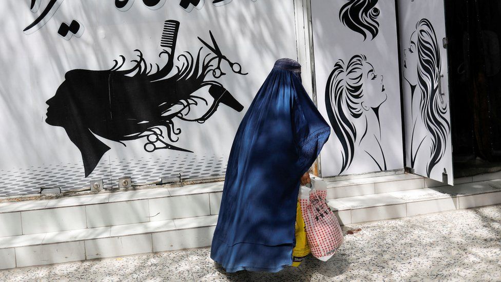 An Afghan woman walks past a beauty salon in Kabul, Afghanistan. Photo: 6 July 2023